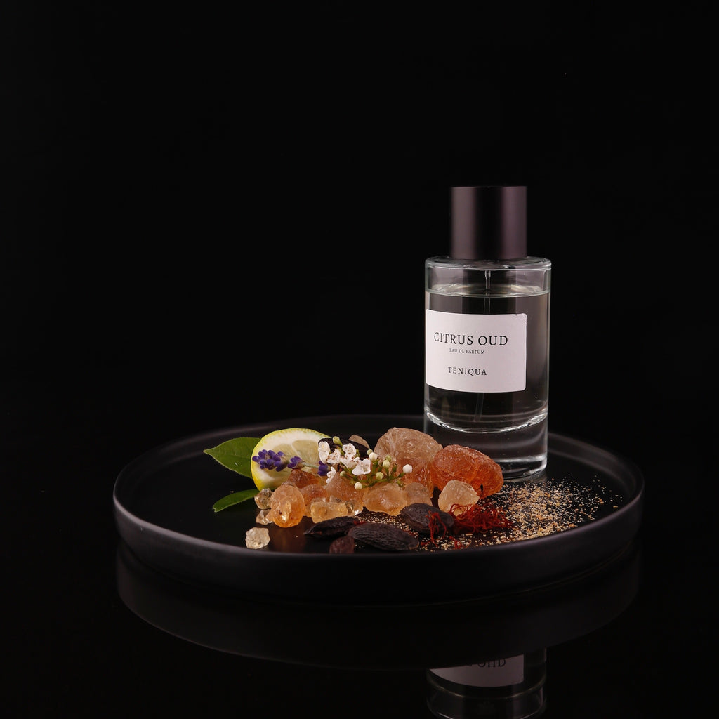 Bottle of Citrus Oud edp on plate with ingredients highlighted against black background
