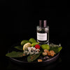Bottle of Figue Verte edp on plate with ingredients highlighted against black background