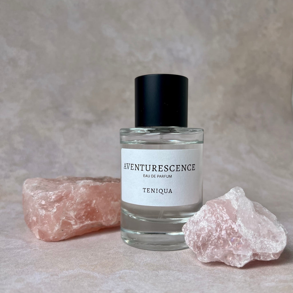 Bottle of Aventurescence perfume with two crystals on a textured surface