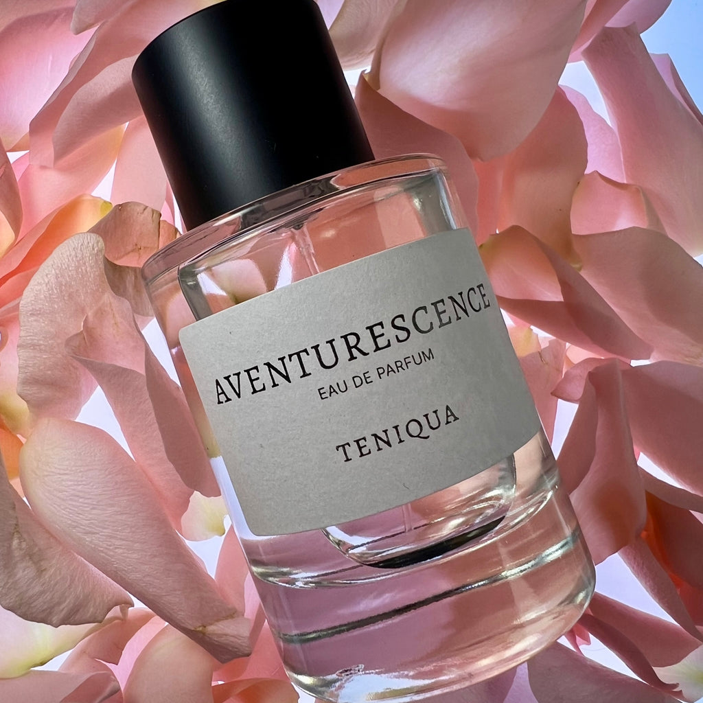Perfume bottle labeled 'Aventurescence Eau de Parfum Teniqua' on pink floral background